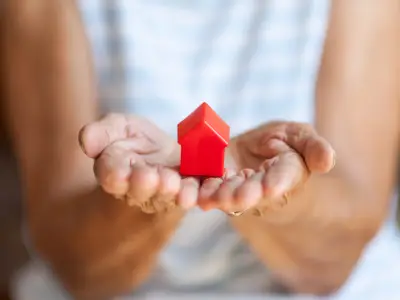 Person holding a small red house model in open hands, symbolizing the cost and value of probate in Texas.