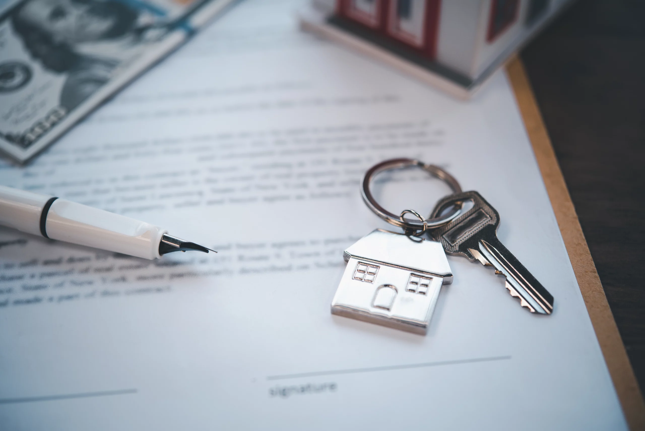 Fountain pen, house key, and contract document symbolizing estate planning and property ownership