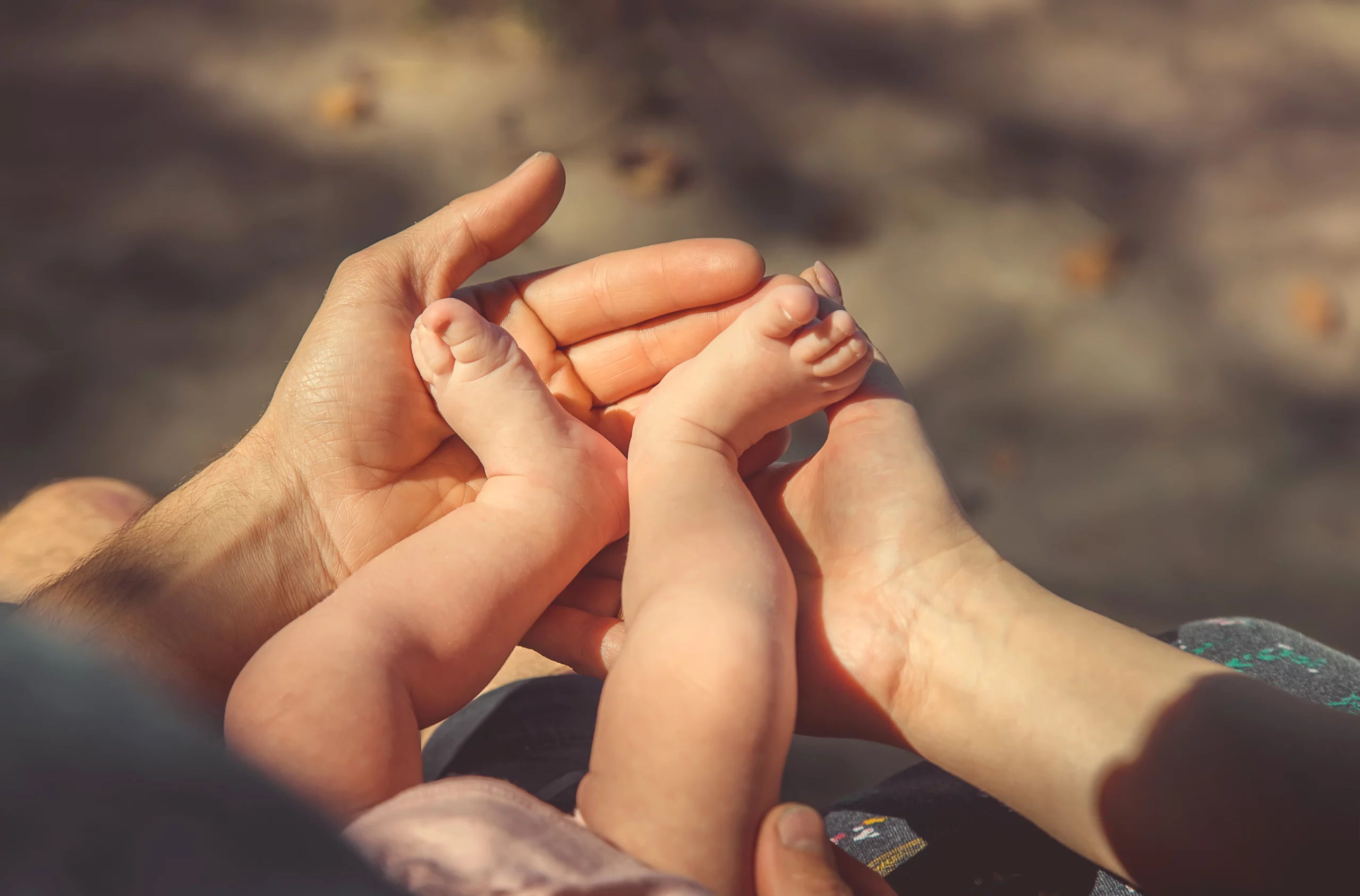 Adult hands gently holding an infant's feet, symbolizing parental care and emotional focus during custody mediation.