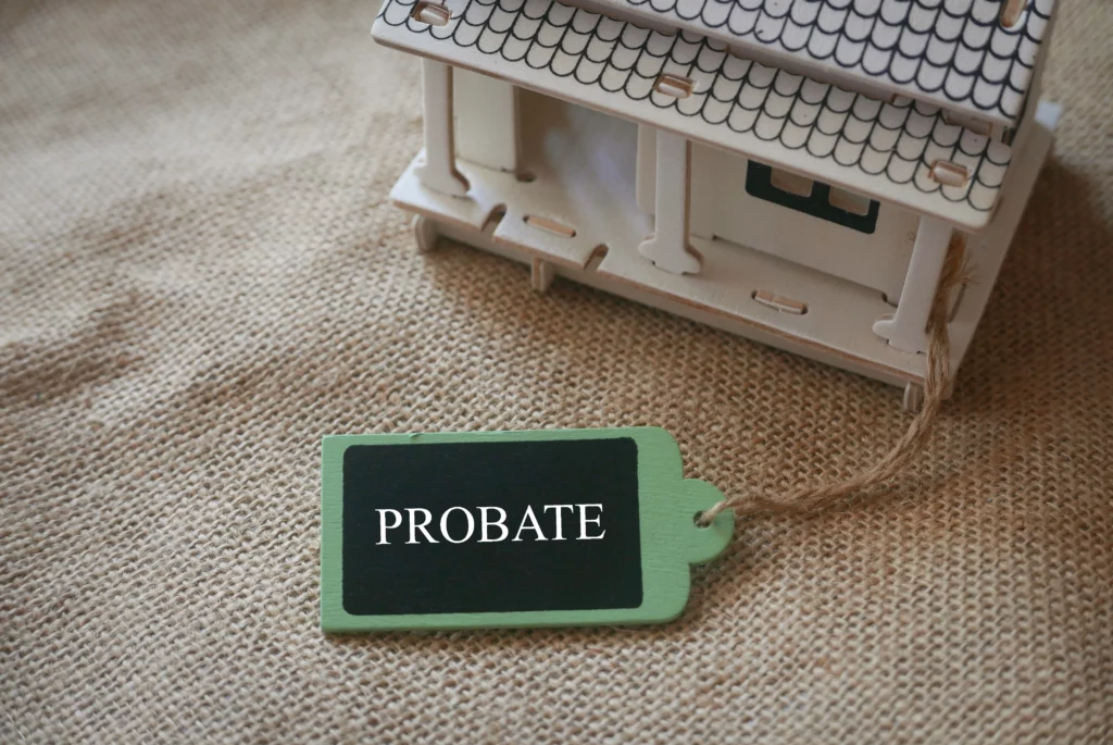 Model house beside tag labeled “Probate” on desk, representing real estate and the distinction between probate and non-probate assets in Texas estate planning