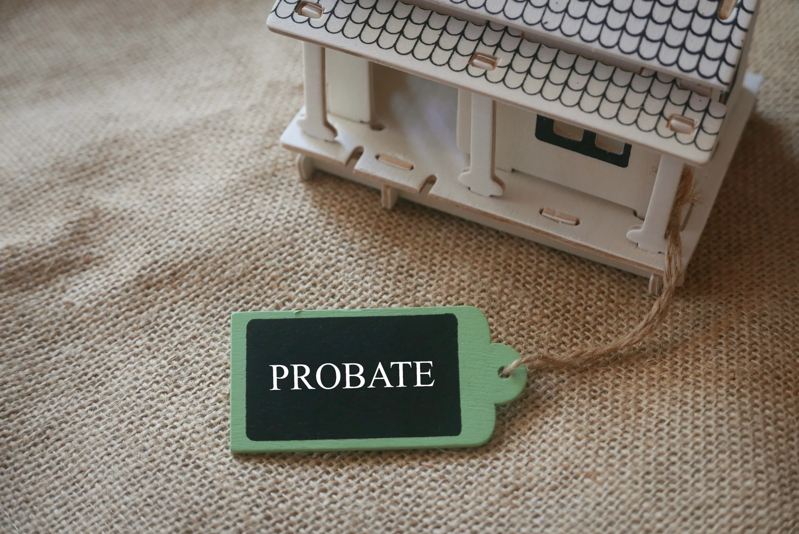 Model house beside tag labeled “Probate” on desk, representing real estate and the distinction between probate and non-probate assets in Texas estate planning