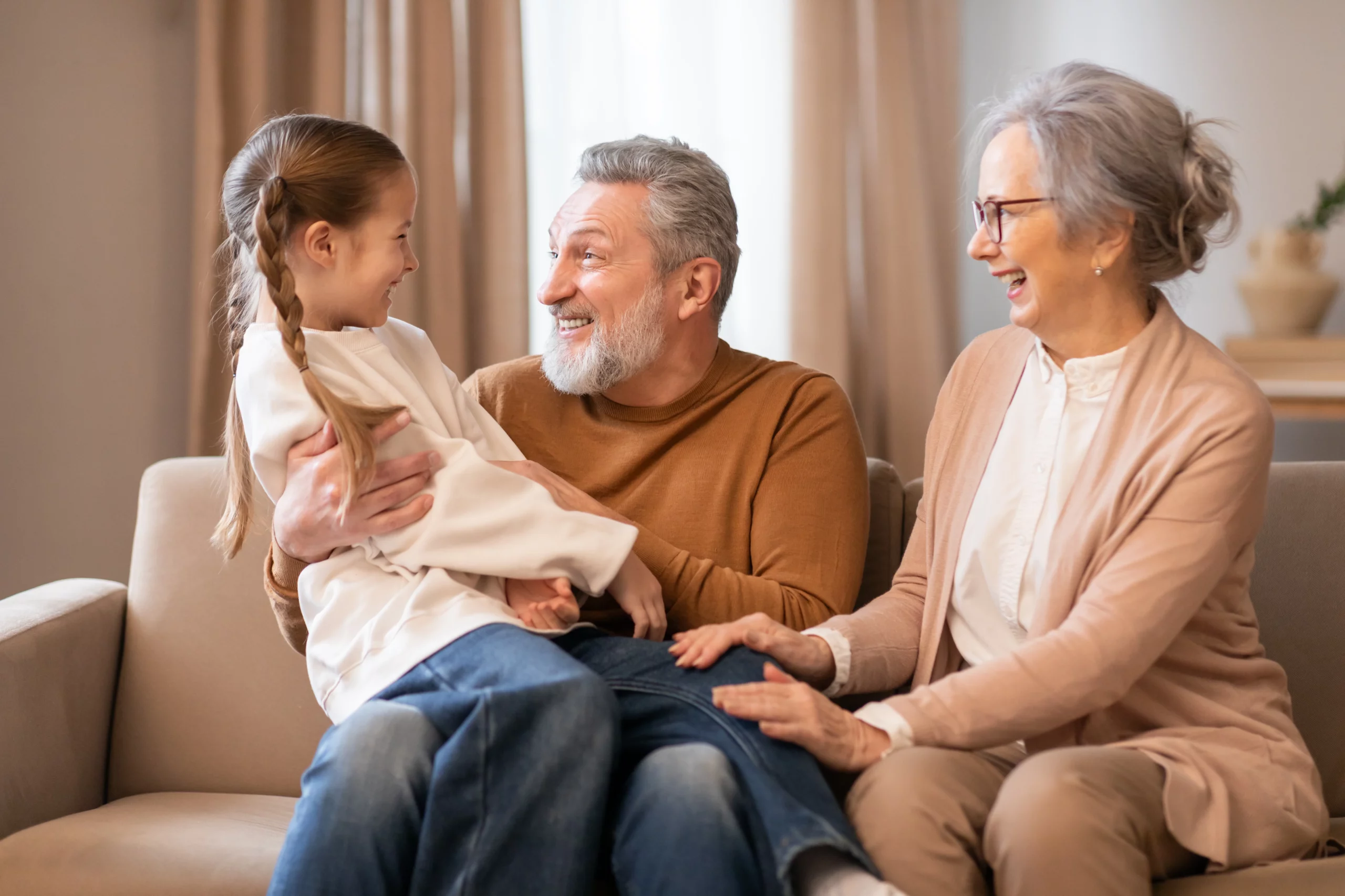 Grandparents embracing their granddaughter on a couch, representing grandparents’ rights in Texas and when visitation or custody may be granted based on the child’s best interests